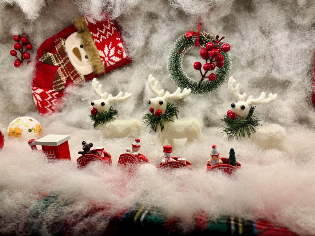 A whimsical Christmas setup featuring reindeer toys, a toy train, and festive decorations.